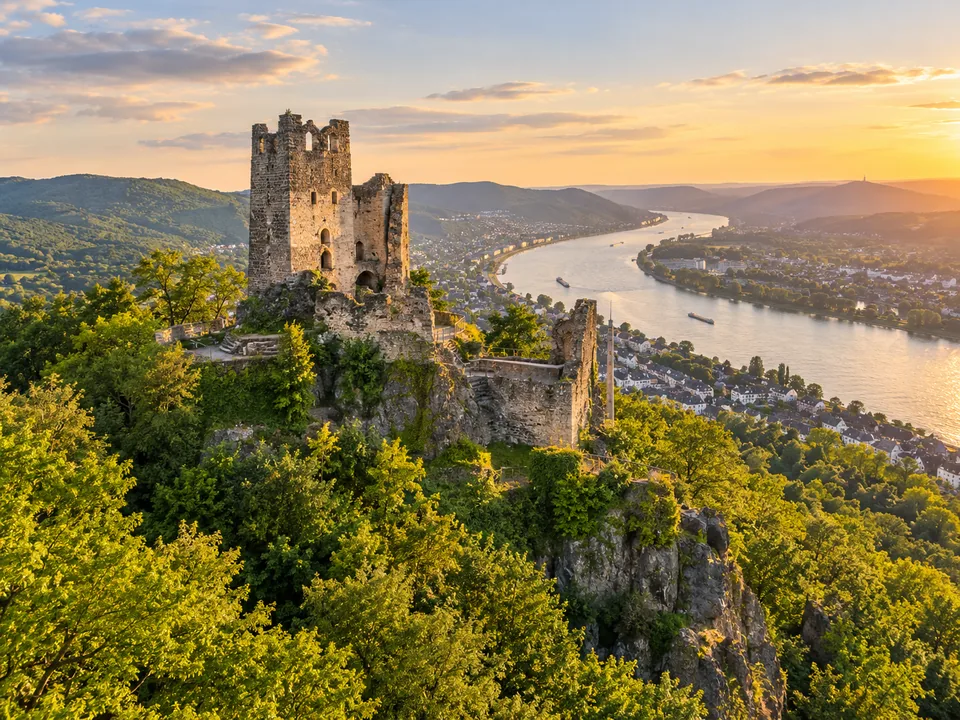 KI-Illustration: Burgruine über dem Rhein im Abendlicht